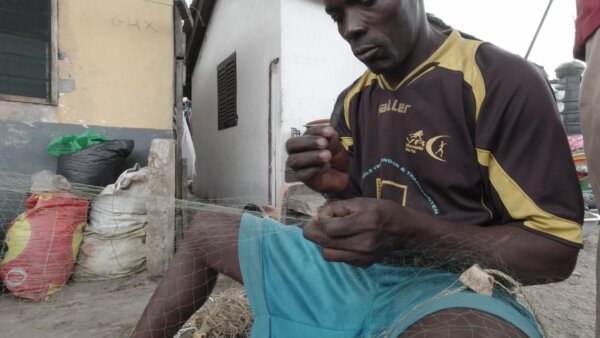 Fisherman Mending Fishing Nets In Front Of House