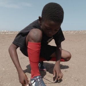 Young Boy Football Player Tightens Boot Lace